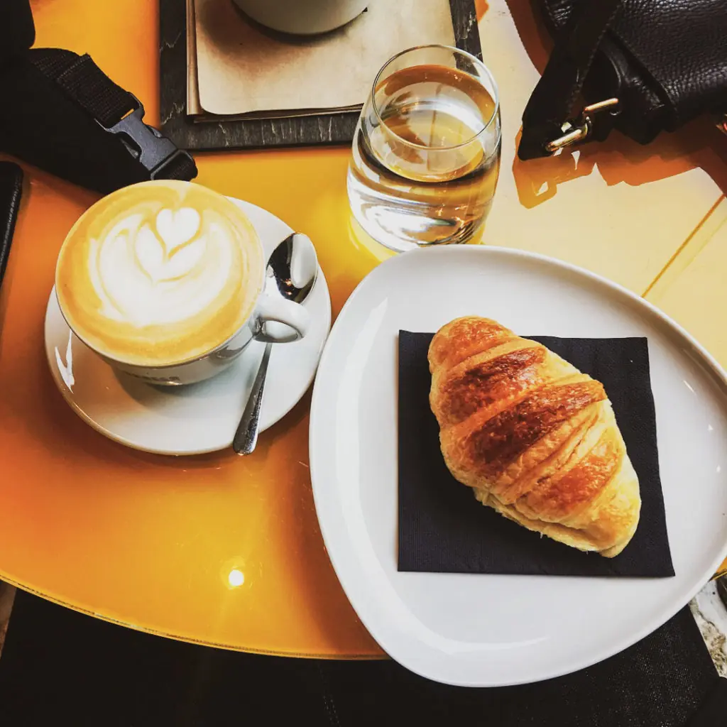 a croissant and a cup of coffee on a plate