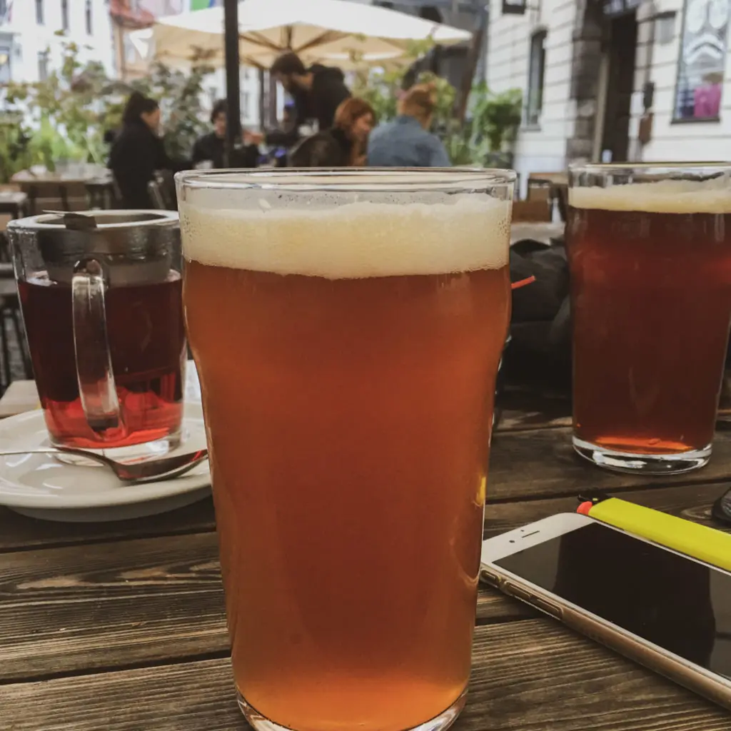 two pints of beer and a cup of tea on a wooden table