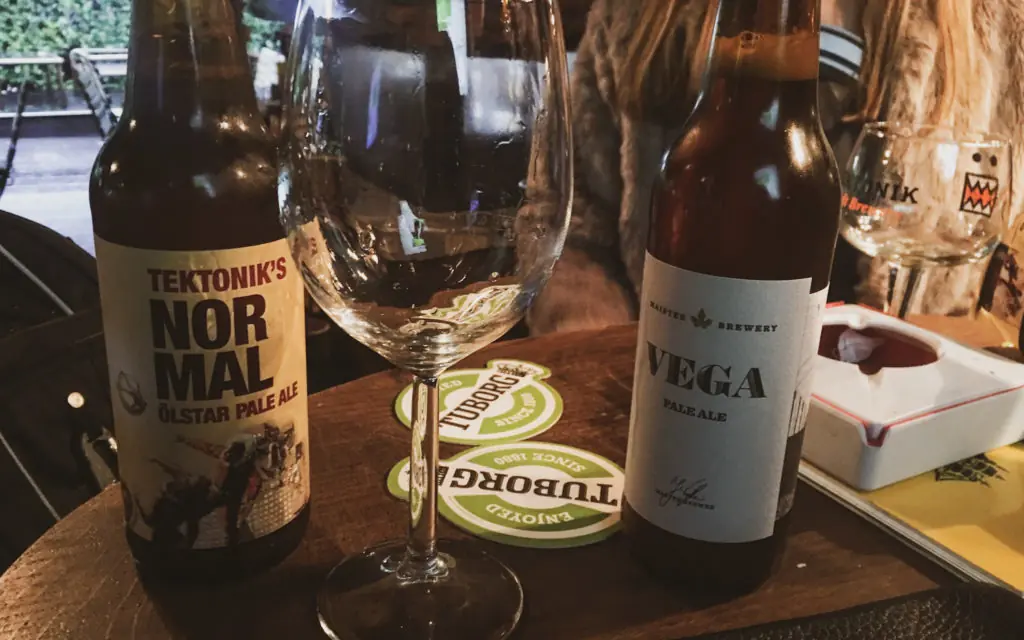 two beer and an empty wine glass on a wooden table