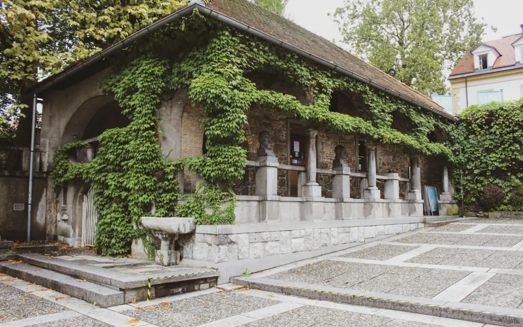 a building with a stone wall and stone pillars covered in ivy