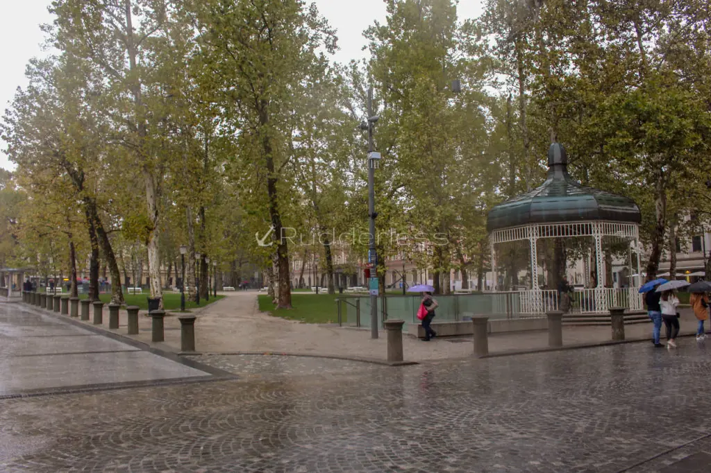 people walking along a stone walkway with umbrellas in a park