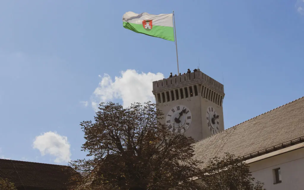 white and green flag flying on top of Ljubljana Castle