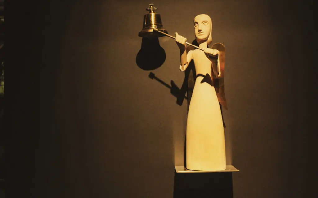 puppet standing on a shelf holding a rope tied to a bell