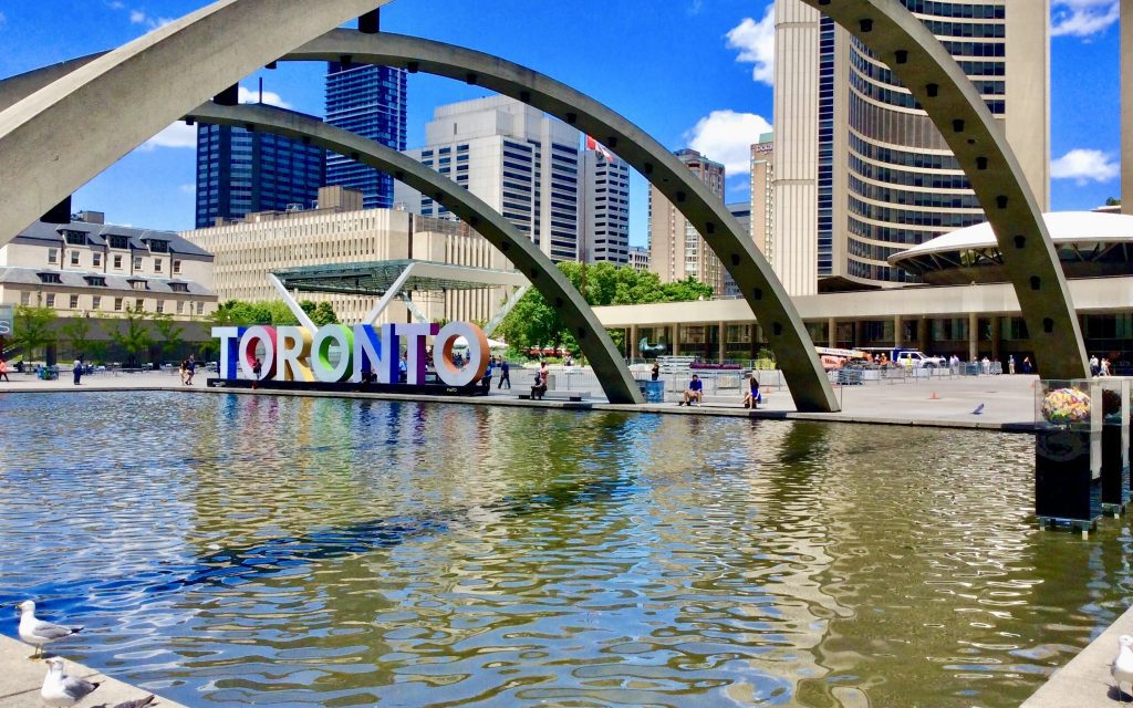 the Toronto sign, featuring white letters with rainbow coloured sides, on display in Nathan Phillips Square