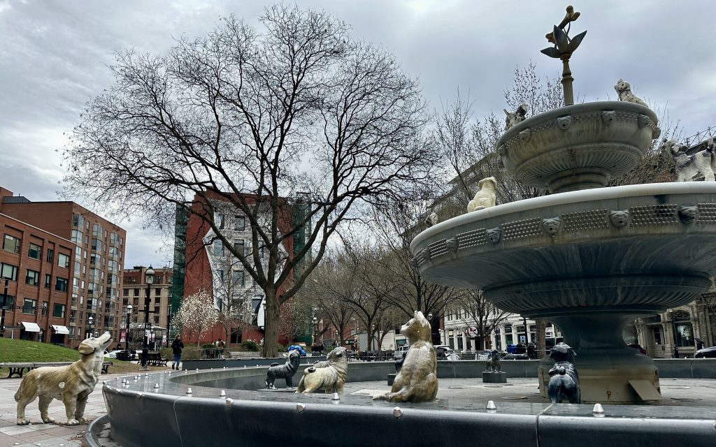 several cast-iron dog statues in and around an outdoor fountain in the park
