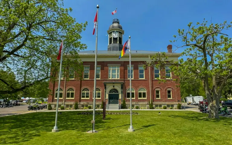 large brick building with many windows and flag poles on the front lawn in Port Hope, Ontario