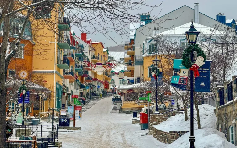 things to do in mont tremblant - a snowy street with buildings and trees